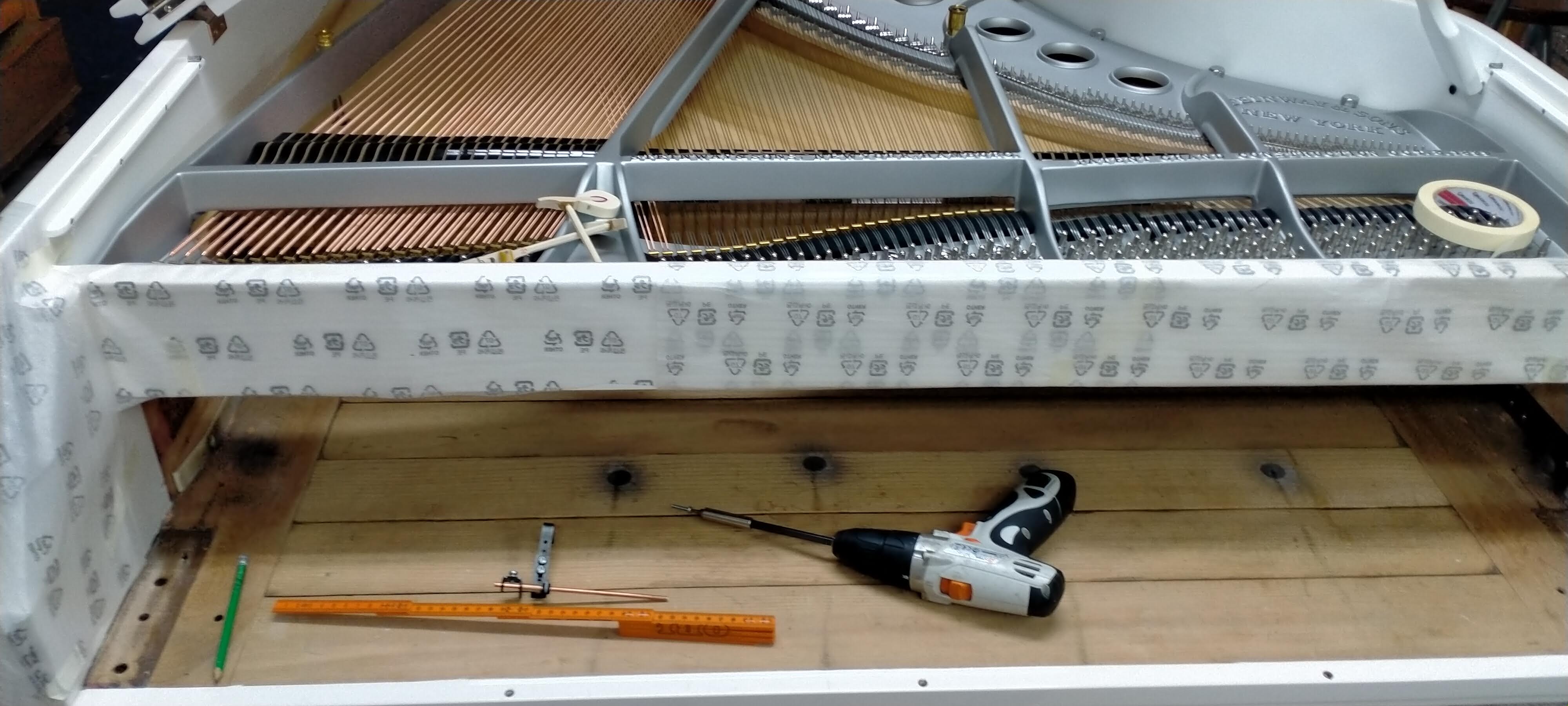 Piano de cola blanco Steinway en restauración con herramientas de trabajo