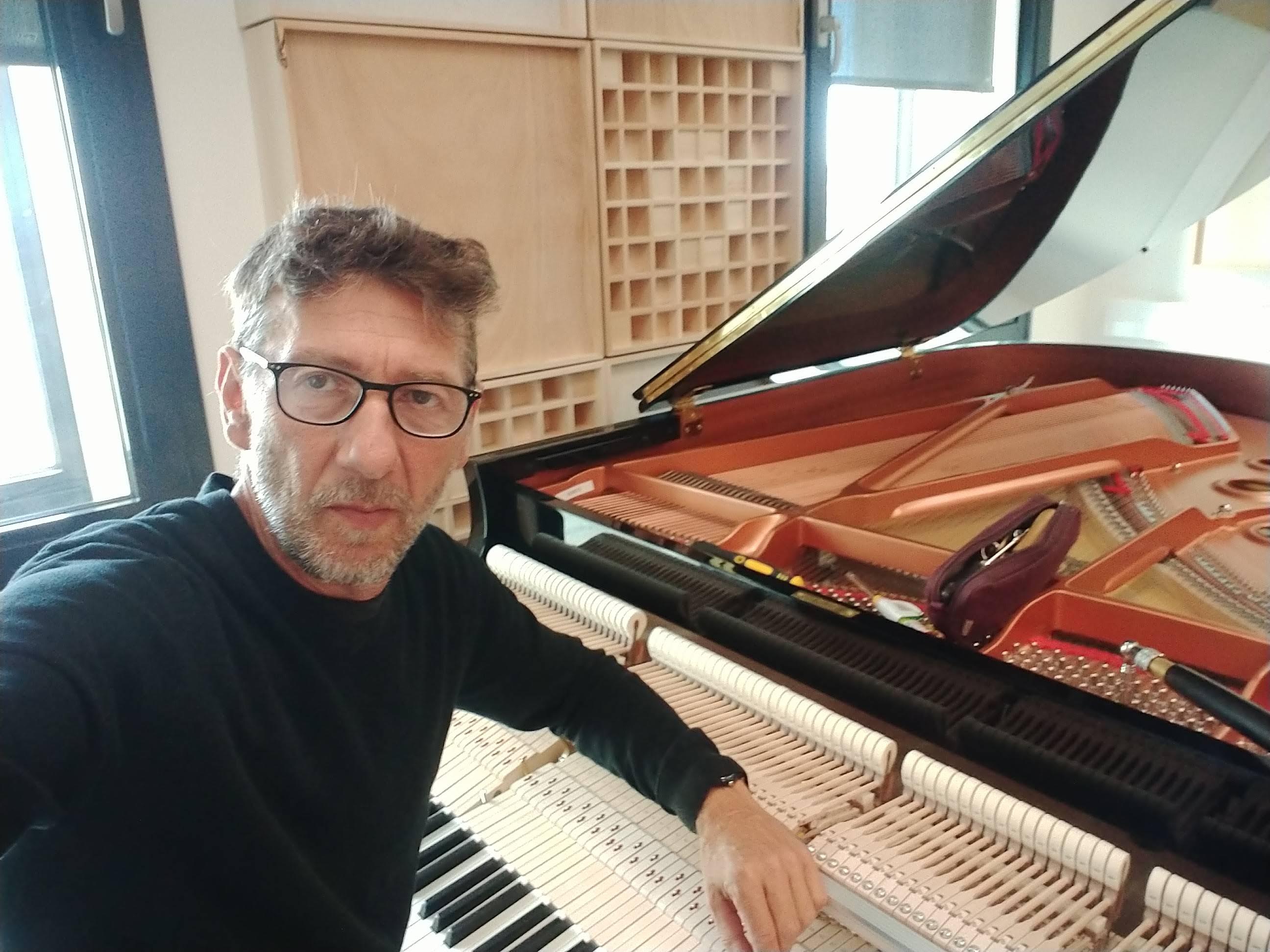 Gonzalo junto a piano de cola con herramientas de afinación